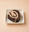 A slice of gluten-free chocolate espresso Swiss roll on a white plate, showing the espresso buttercream spiral inside the chocolate cake