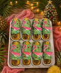 Tray of gluten-free Christmas in July mini cakes topped with green buttercream, sprinkles and a pink flamingo pick